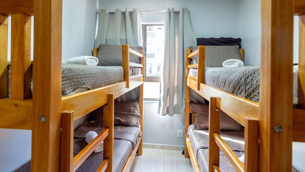 Un dormitorio con literas, una ventana con cortinas y una puerta que da al exterior.