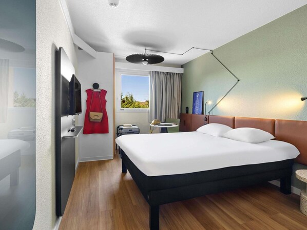 A hotel room with a bed, a desk, a chair, a TV, and a window with a view. - Ibis Budget Auch (Auch)