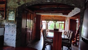 Un espace repas avec un mur en briques, des portes en bois et une table entourée de chaises.