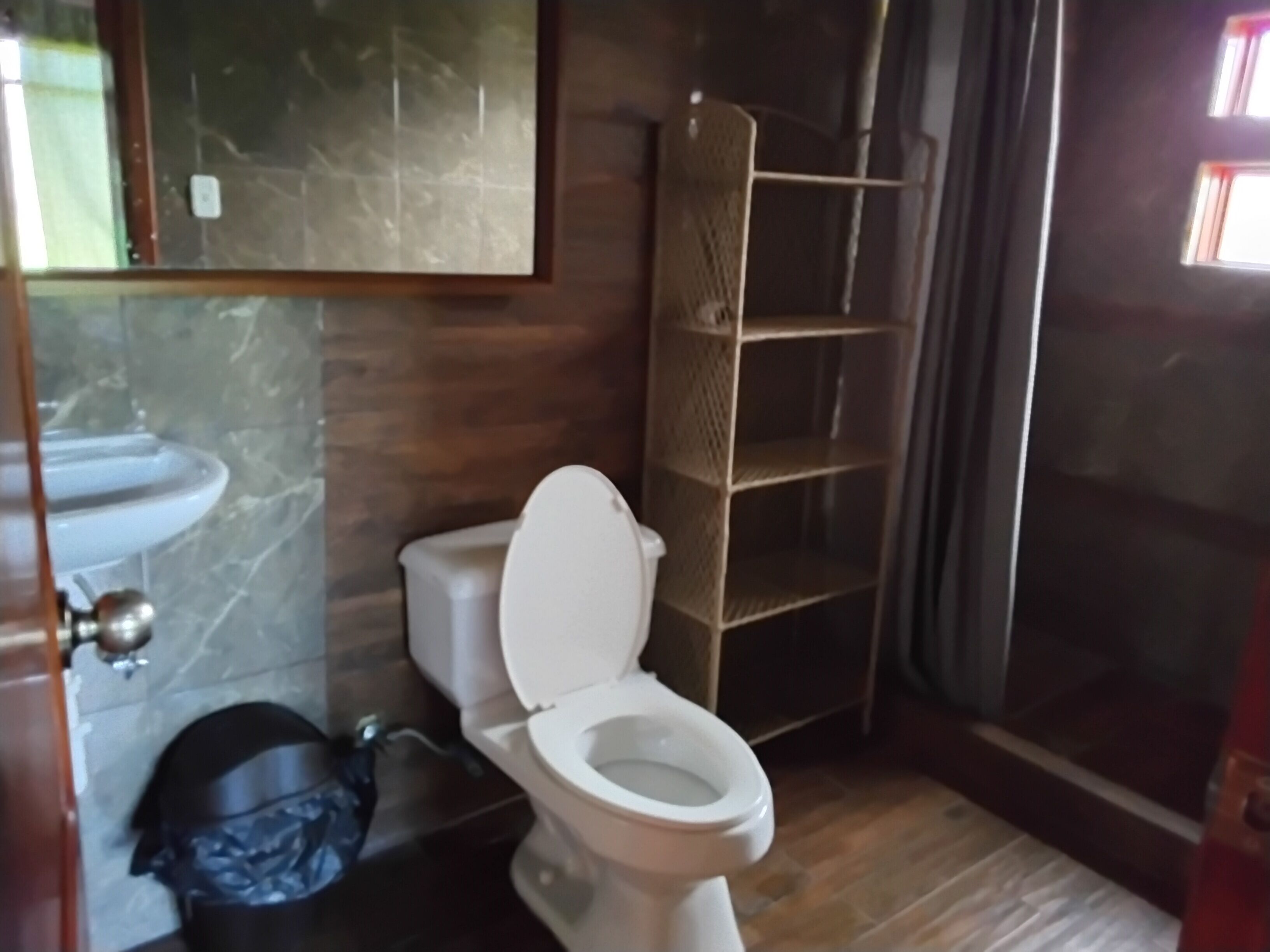 Une salle de bain équipée d’un WC, d’un lavabo, d’un miroir et d’une étagère.