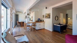 Amplia sala de estar con piso de madera, una mesa de comedor y una zona de cocina con microondas.