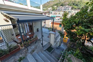 Ein Wohngebäude mit Treppe, einer überdachten Außenbereicherung und Blick auf die umliegende Hanglage.