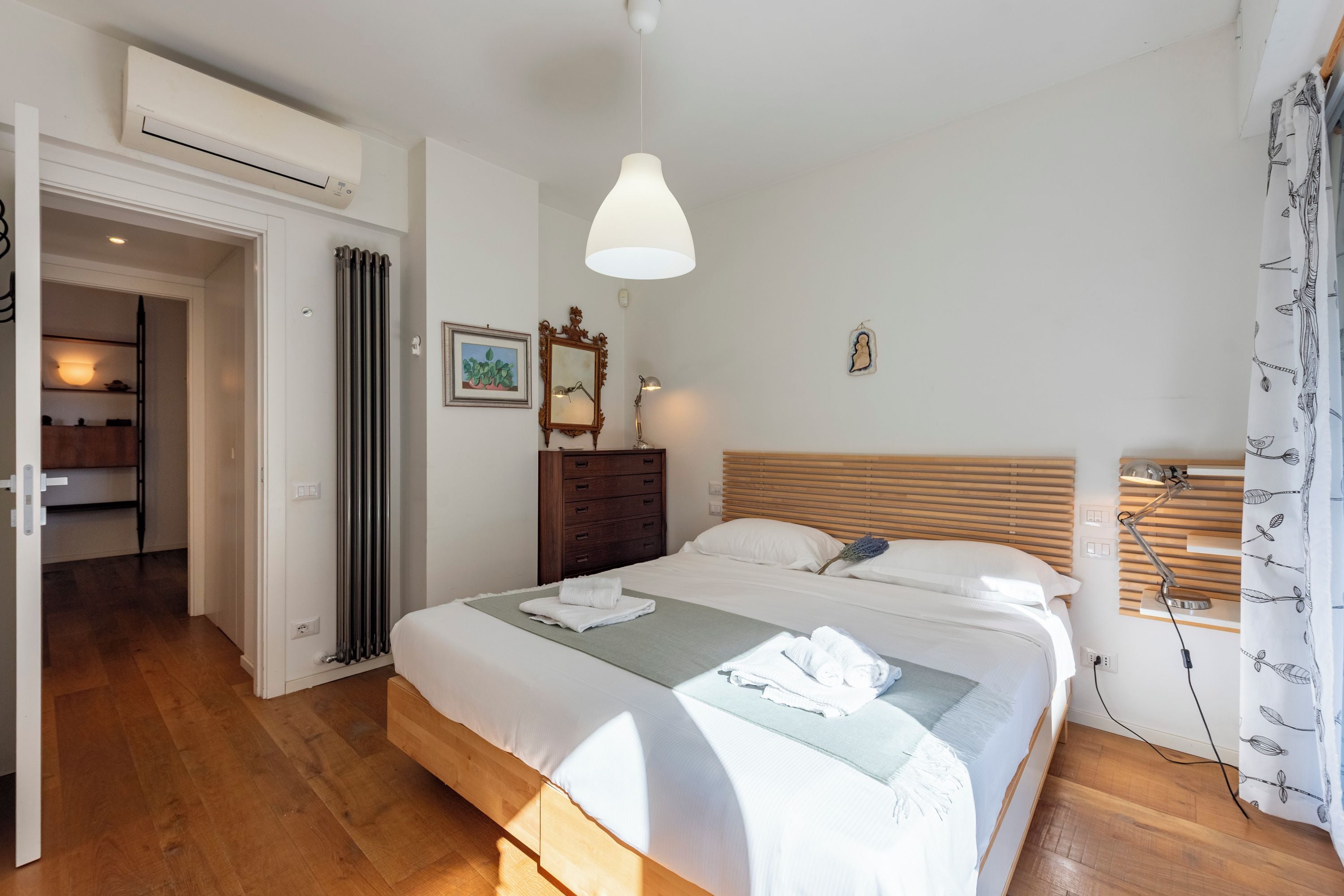 A bedroom with a bed, bedside lamp, and a nightstand.