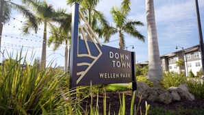 Segnaletica per 'Down Town Wellen Park', con una palma e un edificio sullo sfondo.