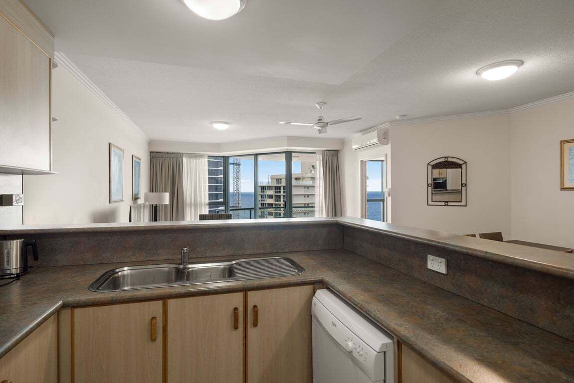 Eine moderne Küche mit eingebautem Geschirrspüler, Spüle und Fenster mit Blick auf die Stadt.