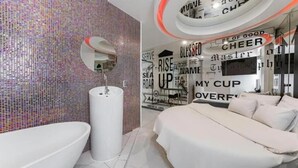 Casa de banho moderna com um espelho grande, uma pia e uma parede decorativa com frases motivacionais.