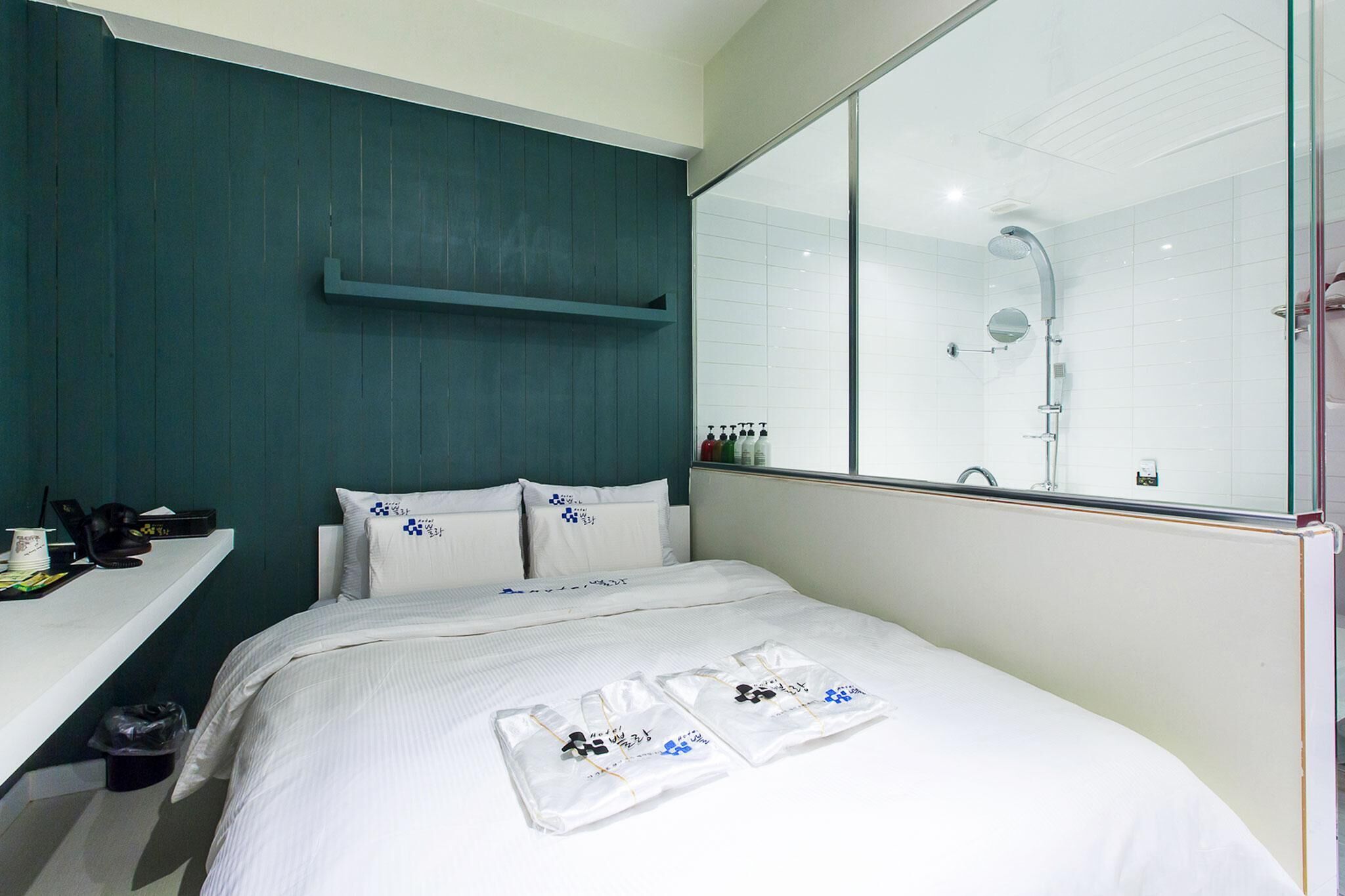 Una habitación de hotel con cama, escritorio, espejo y ducha.