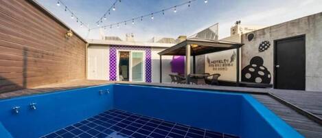 A rooftop pool with a blue interior, a covered seating area, and a sign indicating a hotel.