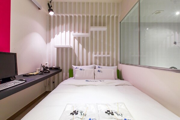A hotel room with a bed, a desk with a computer, and a window. - Plein Hotel (Seoul)