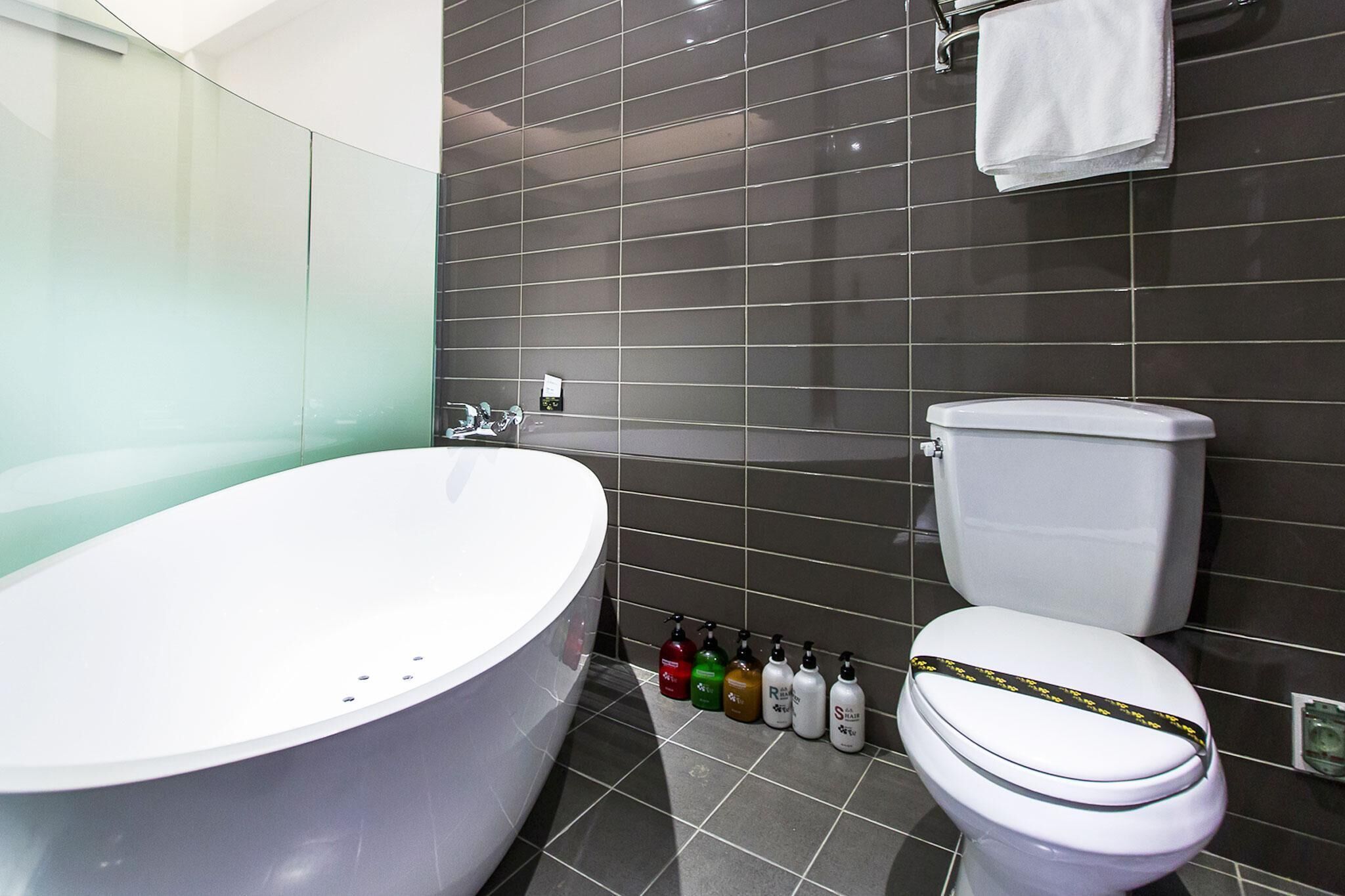 Ein modernes Badezimmer mit einer freistehenden Badewanne, einer Toilette und einer Reihe von Pflegeprodukten.