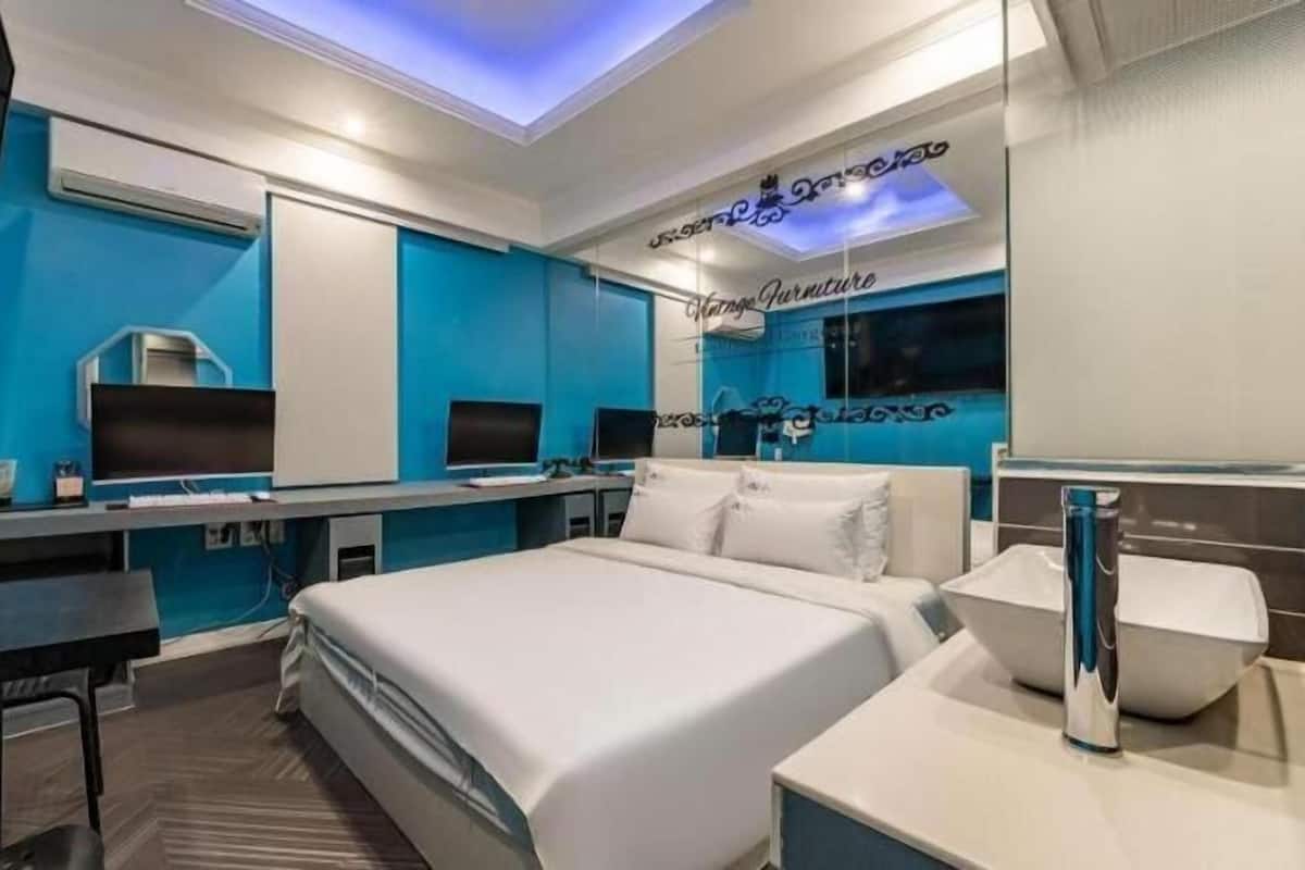 Una habitación de hotel moderna con cama, escritorio y dos monitores.