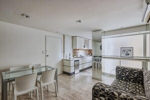 A modern kitchen with a central island, a dining area with a glass table, and a patterned sofa. - Modern & Bright Apartment in Palermo Soho - Great Location (Buenos Aires)