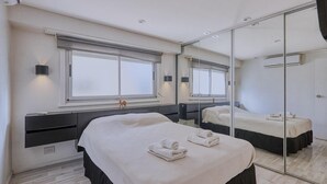 Et moderne hotelværelse med en stor seng, et sengebord, et spejl og et vindue med rullegardiner.