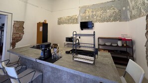 A kitchen with a bar area, a microwave, a coffee maker, and a TV on the wall. - CASA BO | LOFT IN THE HEART OF MEXICO CITY (Ciudad de México)