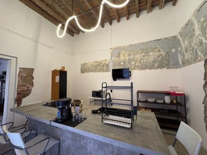 A kitchen with a bar area, a microwave, a coffee maker, and a TV on the wall. - CASA BO | LOFT IN THE HEART OF MEXICO CITY (Ciudad de México)
