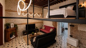 A loft-style room with a bed, sofa, TV, fireplace, and a neon light. - CASA BO | LOFT IN THE HEART OF MEXICO CITY (Ciudad de México)