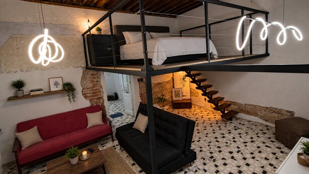 A loft-style room with a bunk bed, a red sofa, a black sofa, and a staircase. - CASA BO | LOFT IN THE HEART OF MEXICO CITY (Ciudad de México)