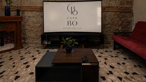 A living room with a stone wall, a TV, a red sofa, and a coffee table with a plant. - CASA BO | LOFT IN THE HEART OF MEXICO CITY (Ciudad de México)