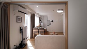Ein modernes Hotelzimmer mit Sofa, Esstisch, Stühlen und einem Staubsauger.