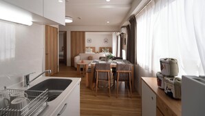 Eine moderne Küche mit Spüle, Esstisch und Stühlen, die in einen Wohnbereich mit Sofa und Essplatz übergeht.