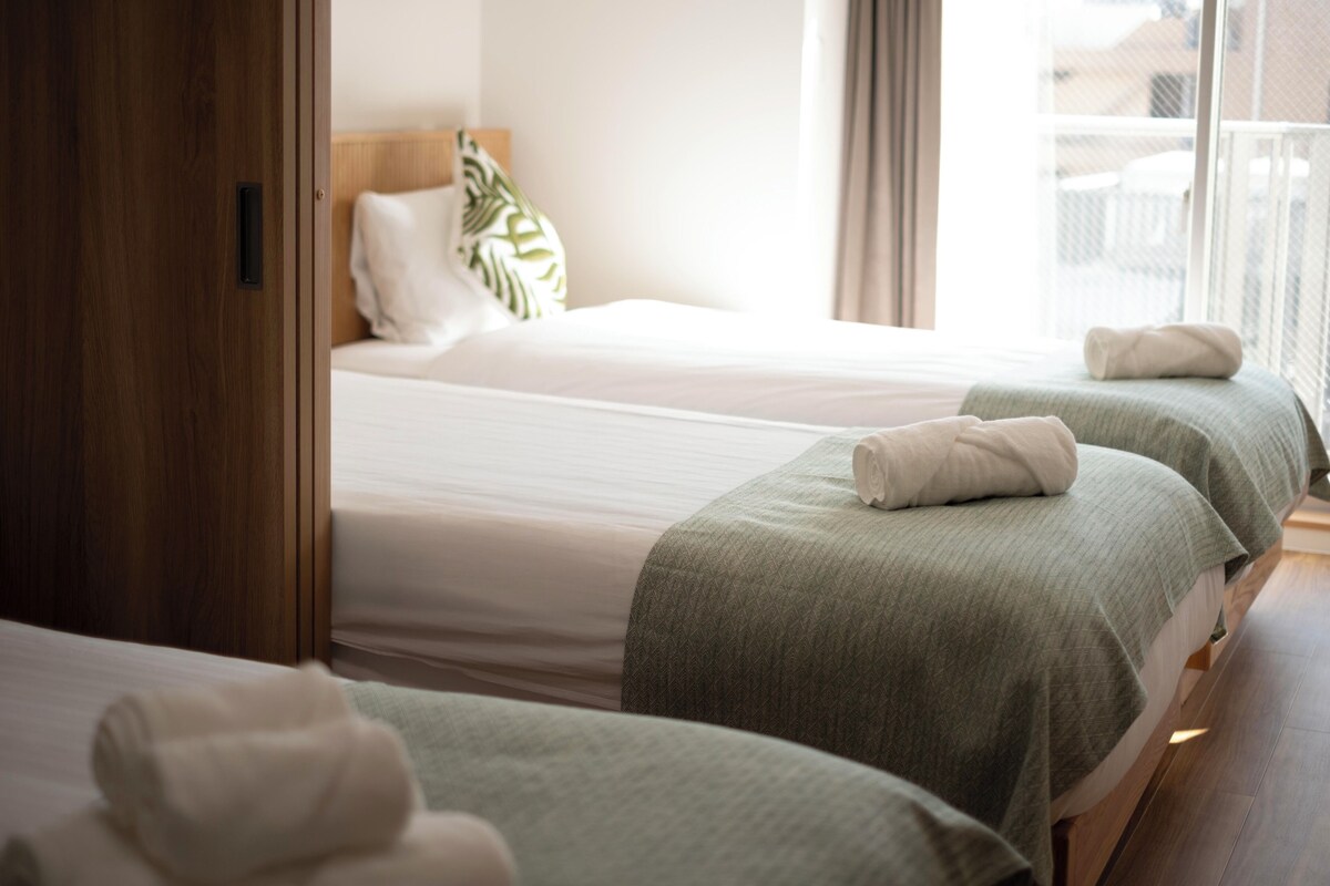 Ein Hotelzimmer mit drei Betten, einem Holzschrank und Blick ins Freie.