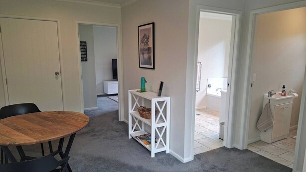 Una habitación con una mesa de comedor de madera, una consola blanca, un armario blanco con una toalla y un cuadro en la pared.