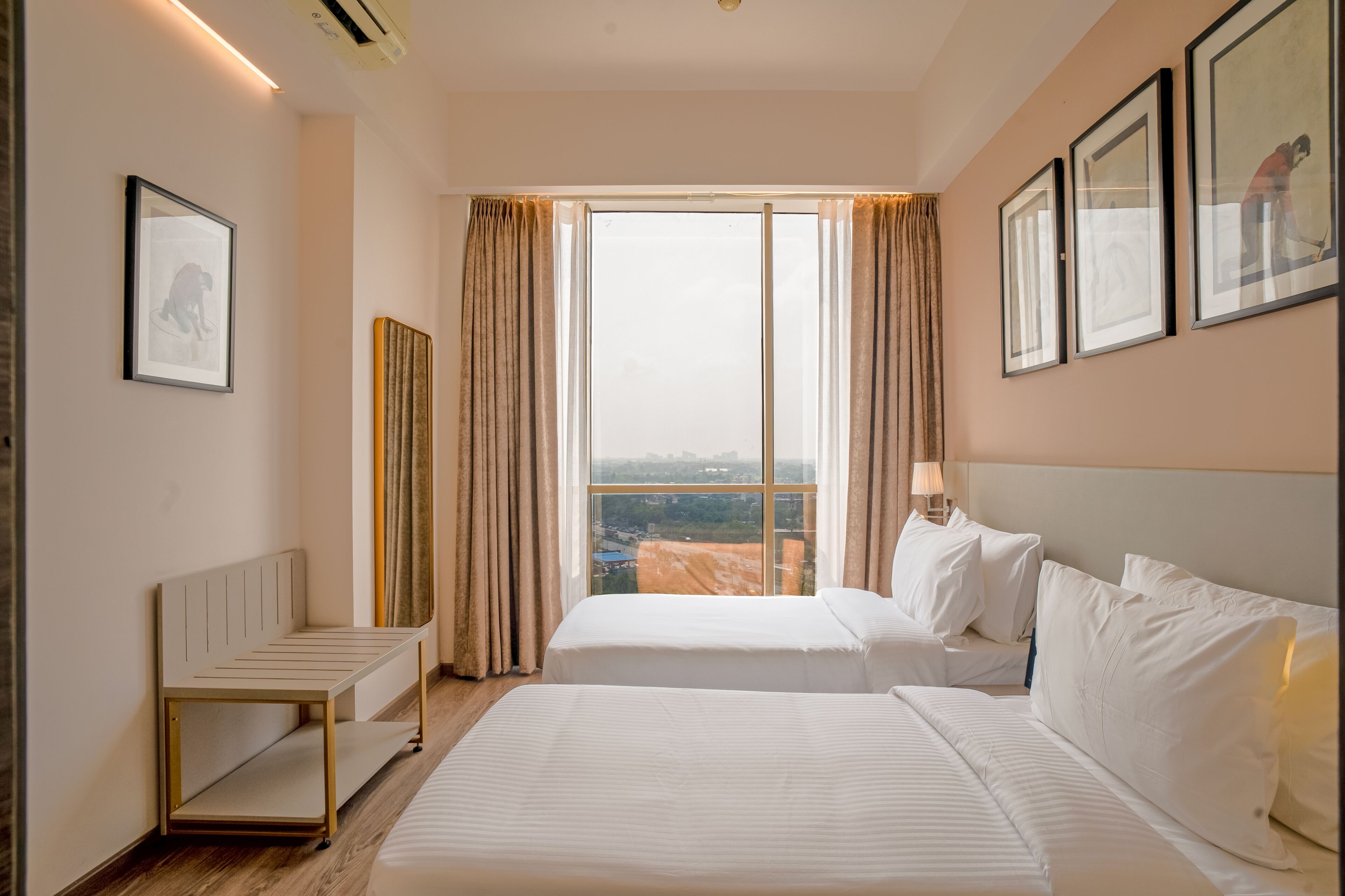 A hotel room with two beds, a desk, and a large window with curtains.