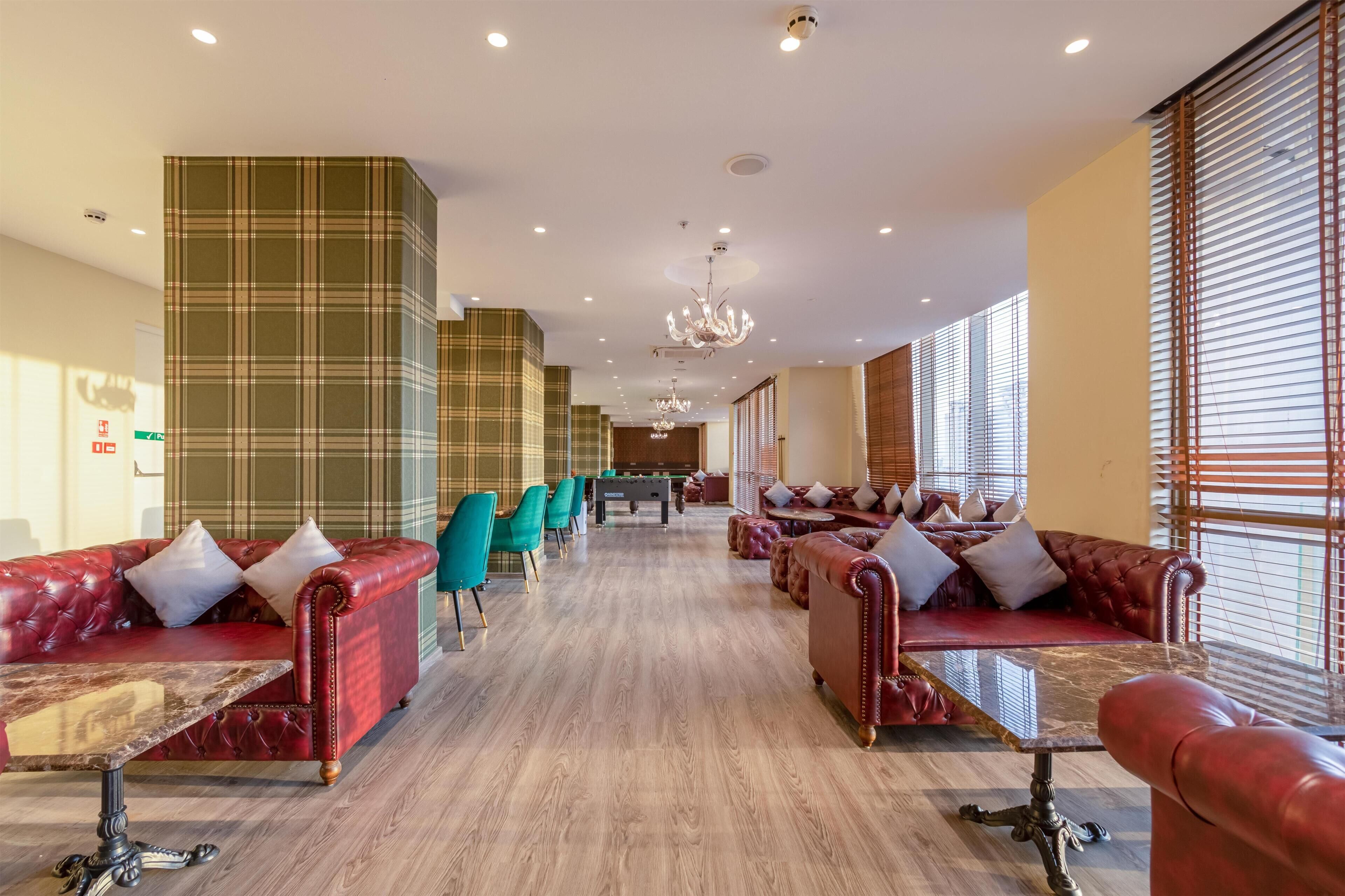 A spacious hotel lobby with leather sofas, a pool table, and a chandelier.