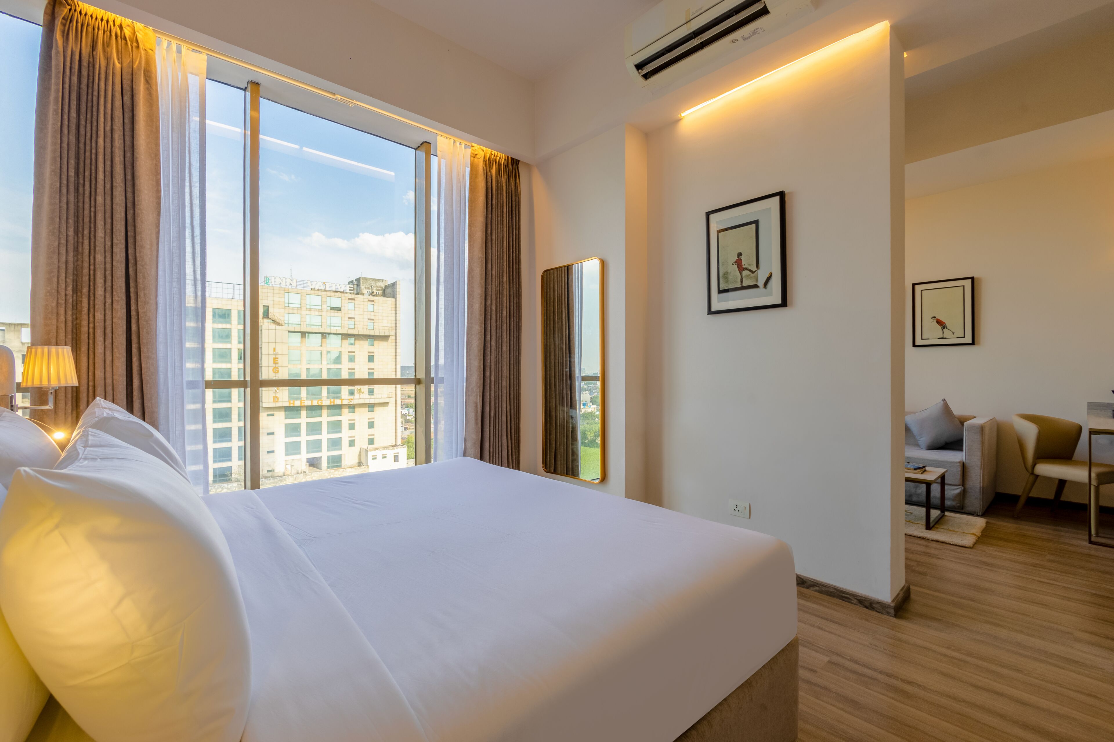 Une chambre d’hôtel avec un grand lit, un bureau et une vue sur le paysage urbain.