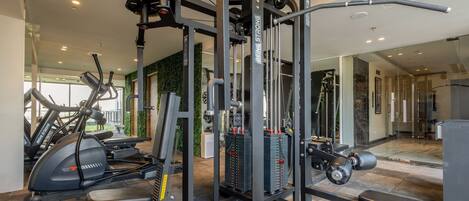Un gimnasio con diversos equipos de ejercicio, como una estación multi-gym, cintas de correr y máquinas de pesas.