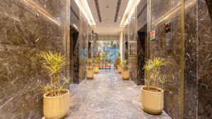 A marble-floored hallway with potted plants and an elevator. - Golden Tulip Gurugram (Gurugram)