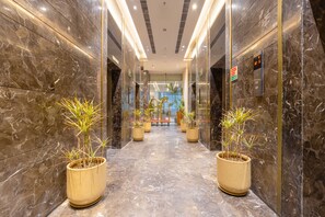 A marble-floored hallway with potted plants and an elevator. - Golden Tulip Gurugram (Gurugram)