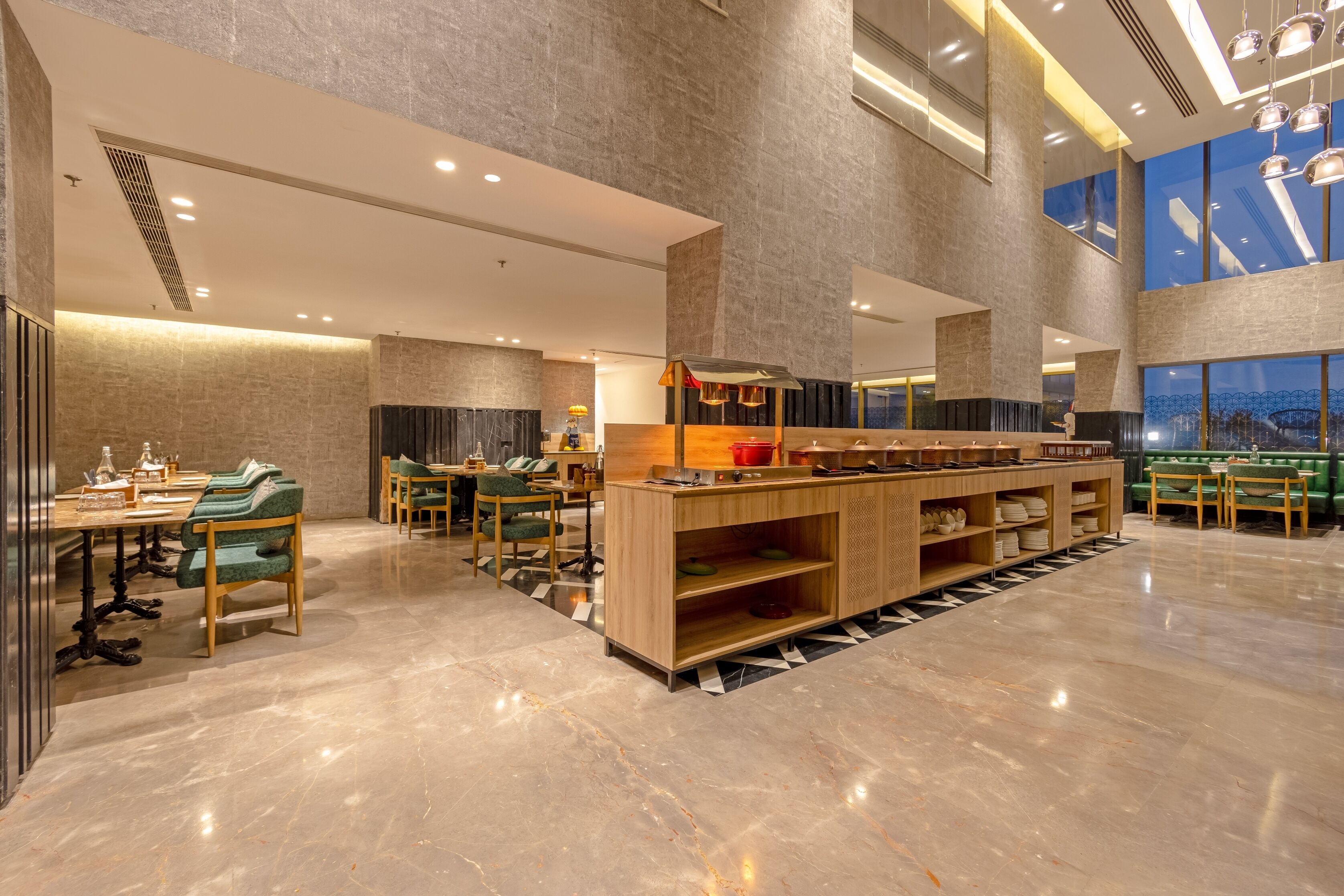 Un amplio vestíbulo de hotel con un bar central, zonas de estar y grandes ventanales.