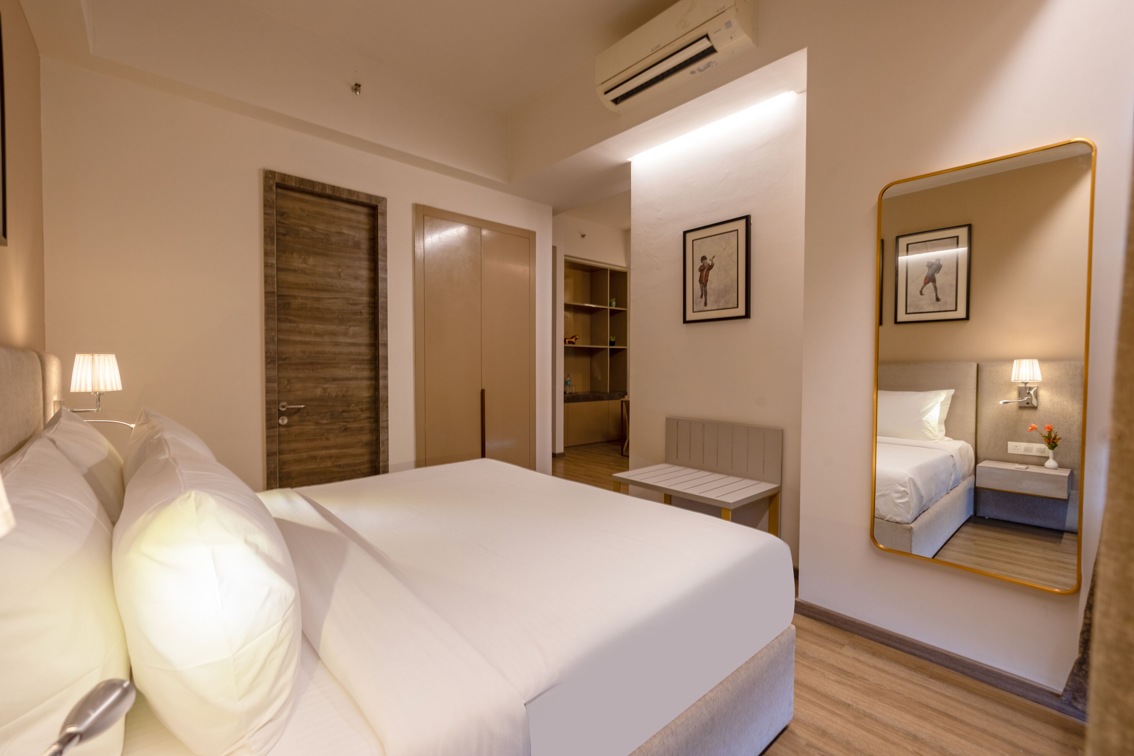 Une chambre d’hôtel comprenant un lit, des tables de chevet, un miroir et une armoire.