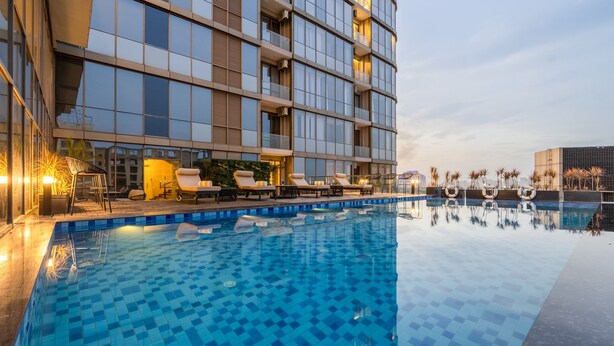 Een modern hotel met een zwembad, ligbedden en uitzicht op de stadshemel.