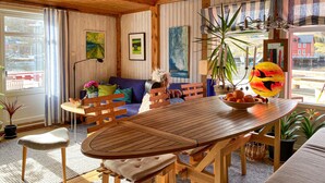 A cozy room with a wooden dining table, a sofa, and a window with a view of boats.