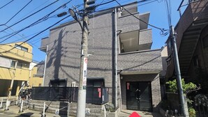 A multi-story building with a brick facade, a visible entrance, and a security gate. - Gold Mansion Apartments (Tokyo)