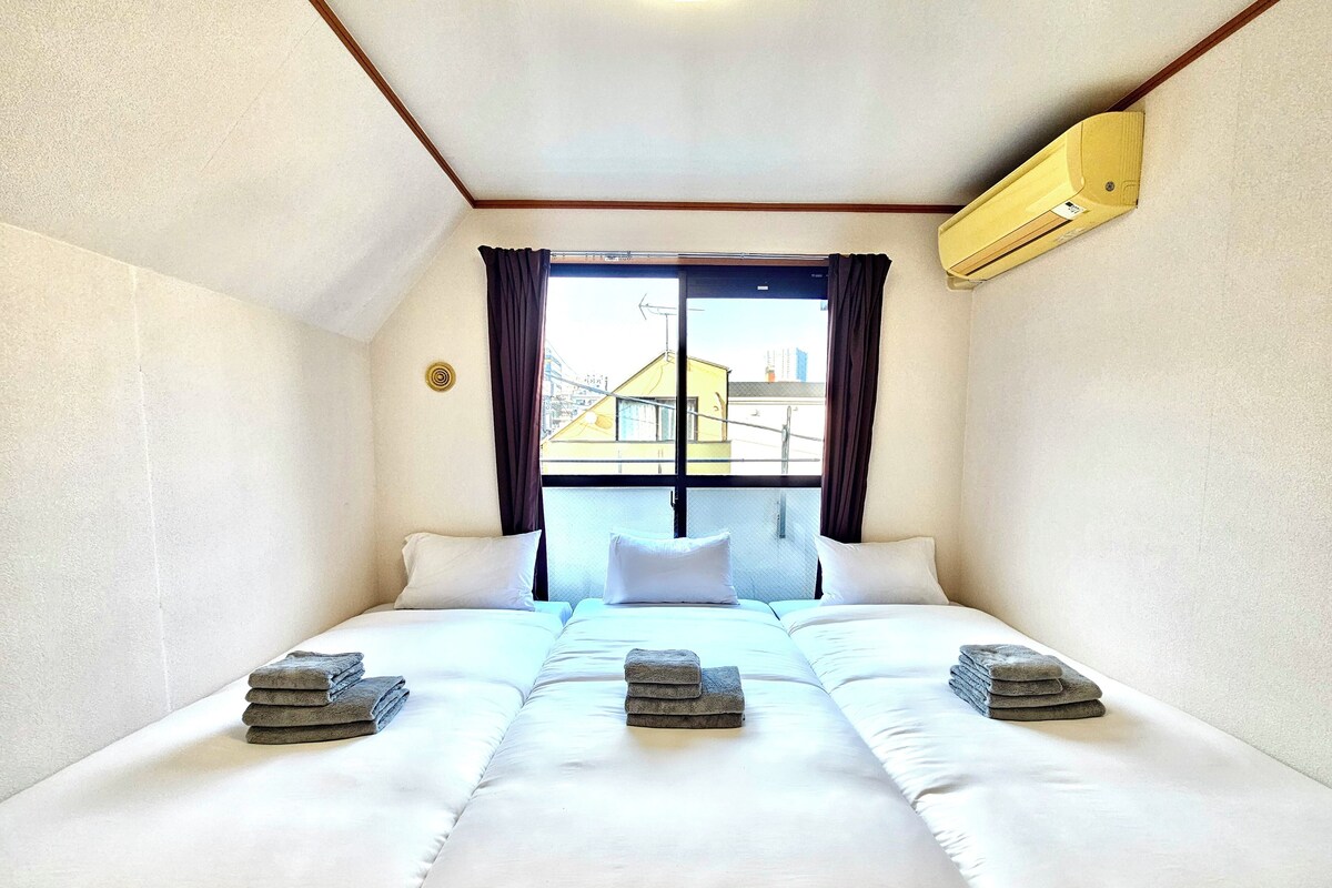 A hotel room with a large bed, two pillows, and a window with curtains.