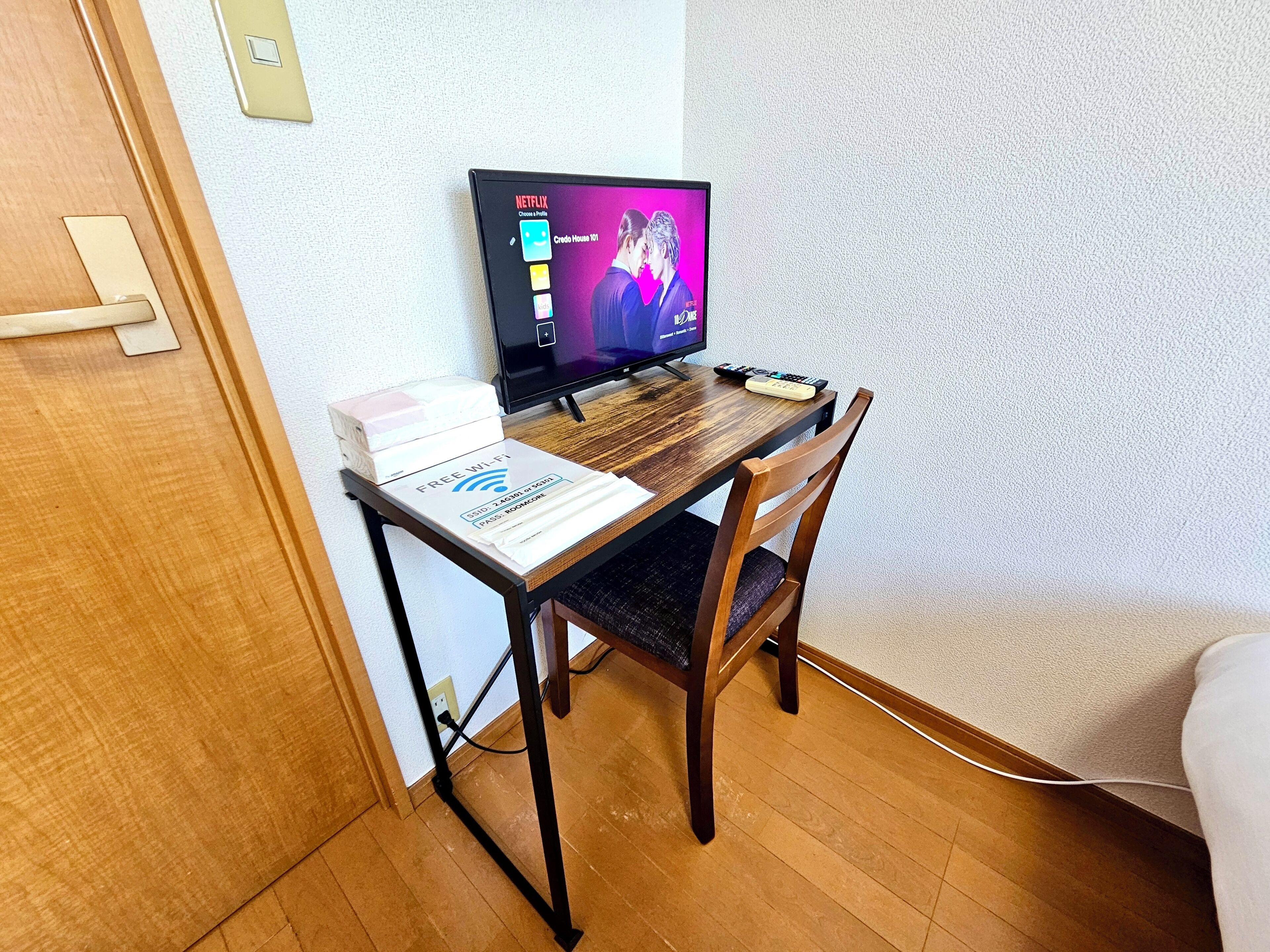 A small wooden desk with a laptop, a remote control, and a box labeled 'FREE WIFI'.