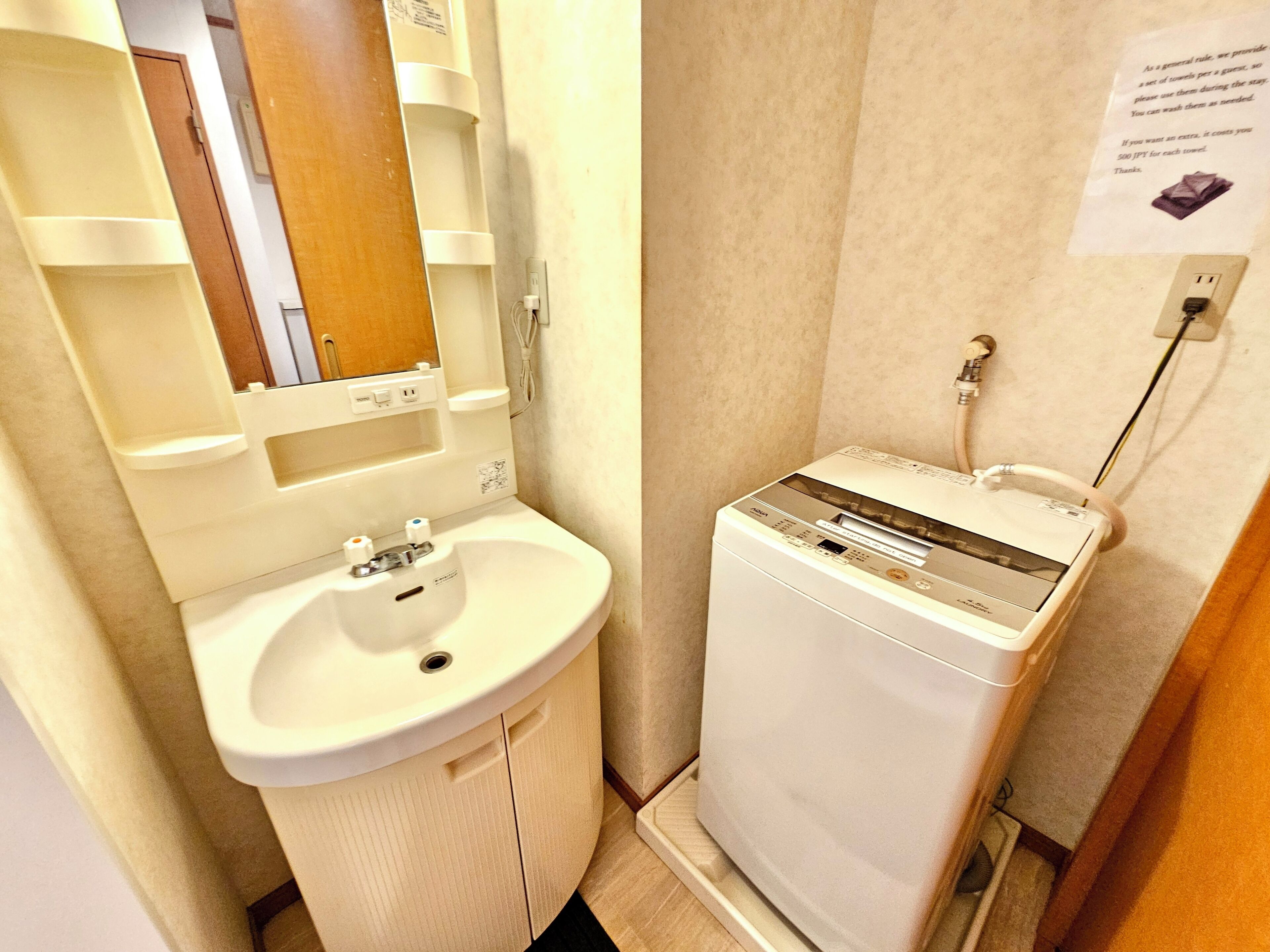 A bathroom with a sink, mirror, and a white washing machine.