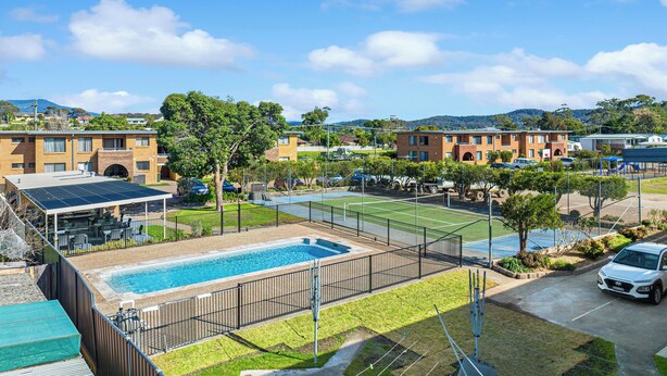A residential area with a swimming pool, tennis courts, and a parking lot. - Apollo Holiday Units (Narooma)