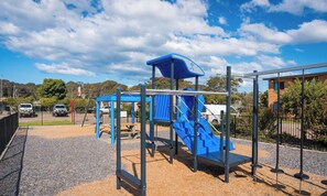 Un parque infantil con un tobogán azul y estructuras para escalar.