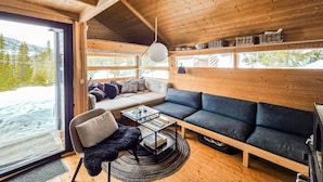 Et hyggeligt stuékammer med sofa, lænestol og et bord med bøger.