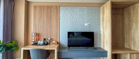 A modern room with a wooden desk, a chair, a TV, and a potted plant.