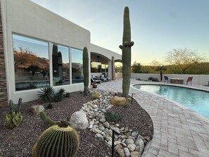 Ein modernes Haus mit Pool, umgeben von Kakteen und Felsen.