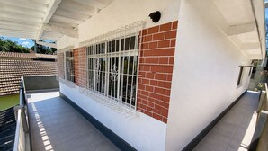 A building with a white exterior, a brick section, and a metal fence.