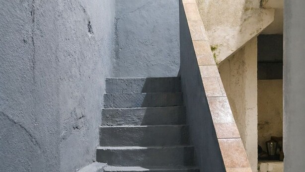 A concrete staircase with a handrail, leading to a higher level.