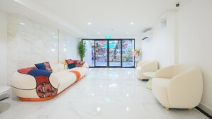 A modern lobby with a marble floor, a colorful sofa, and a white armchair. - Global Hotel Pratunam Bangkok (Bangkok)