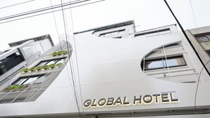 A building with a sign reading 'GLOBAL HOTEL' and multiple windows with green plants. - Global Hotel Pratunam Bangkok (Bangkok)