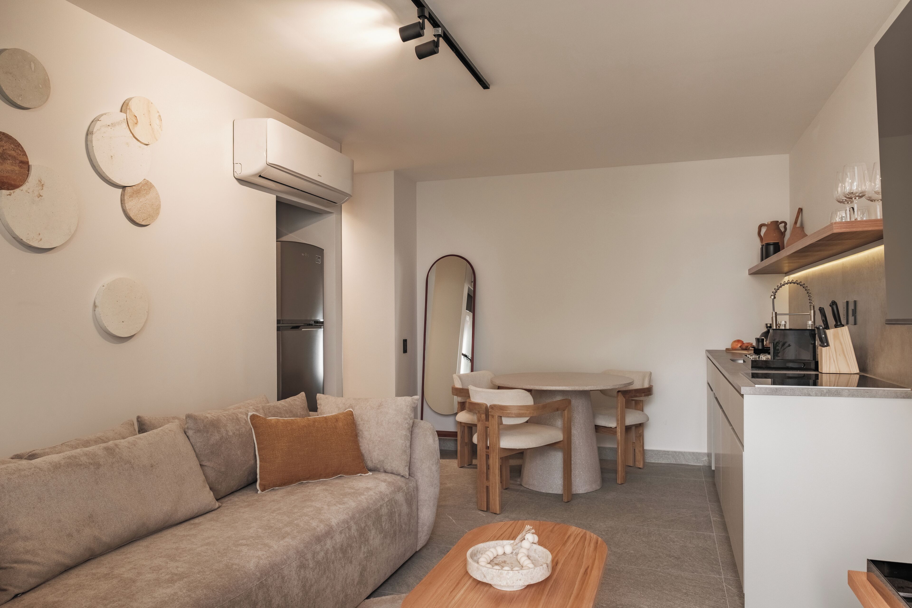A modern living space with a sofa, a dining table, and a kitchen area.